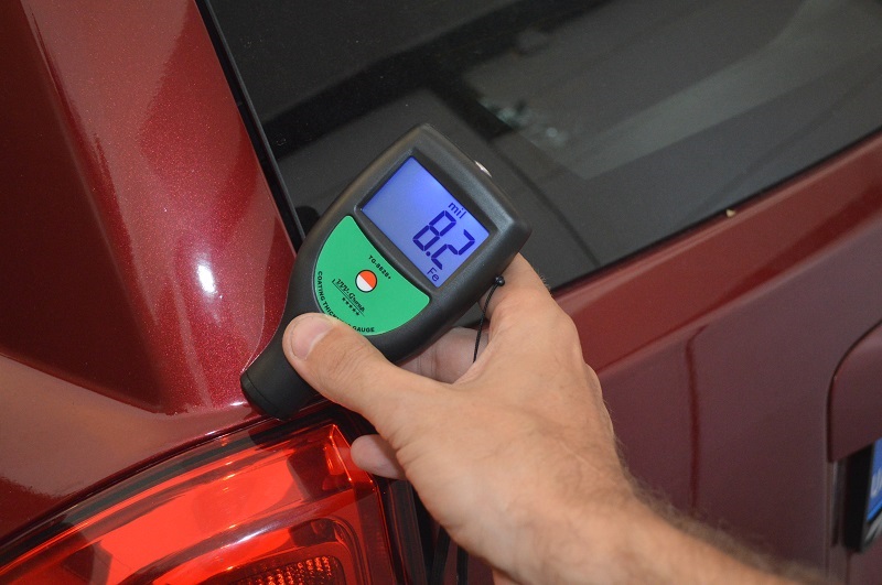 Paint thickness gauge measuring car body panel to detect repaint and hidden repairs