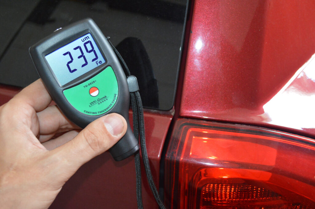 TG-8828 paint thickness gauge measuring 239 microns on a steel car body panel (Fe) during used car inspection
